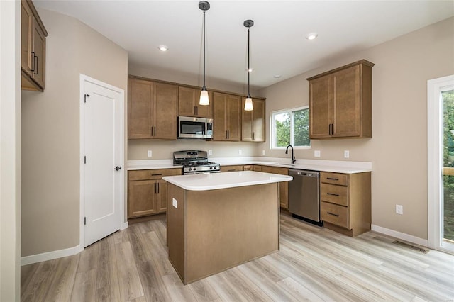 kitchen featuring a kitchen island, light countertops, appliances with stainless steel finishes, brown cabinetry, and pendant lighting