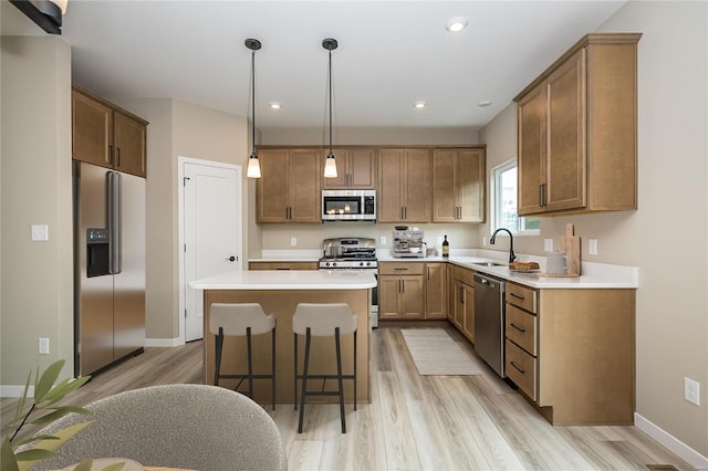 kitchen featuring pendant lighting, stainless steel appliances, a kitchen island, and light hardwood / wood-style flooring