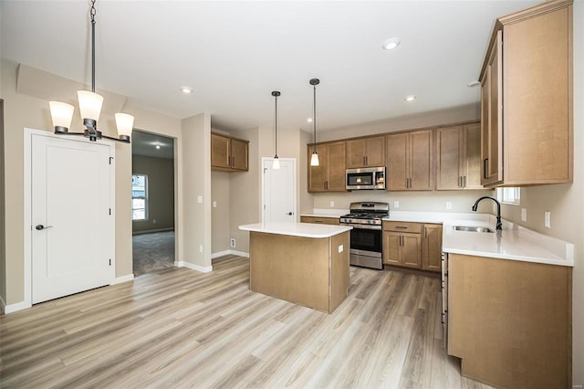 kitchen featuring a center island, decorative light fixtures, light countertops, appliances with stainless steel finishes, and a sink