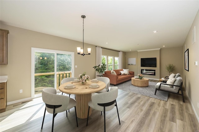 dining room with light wood-type flooring, baseboards, and a glass covered fireplace