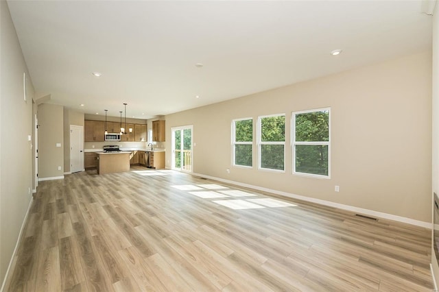 unfurnished living room with light wood-type flooring, baseboards, and recessed lighting