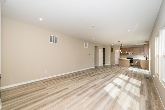 unfurnished living room with baseboards, visible vents, and light wood-style flooring