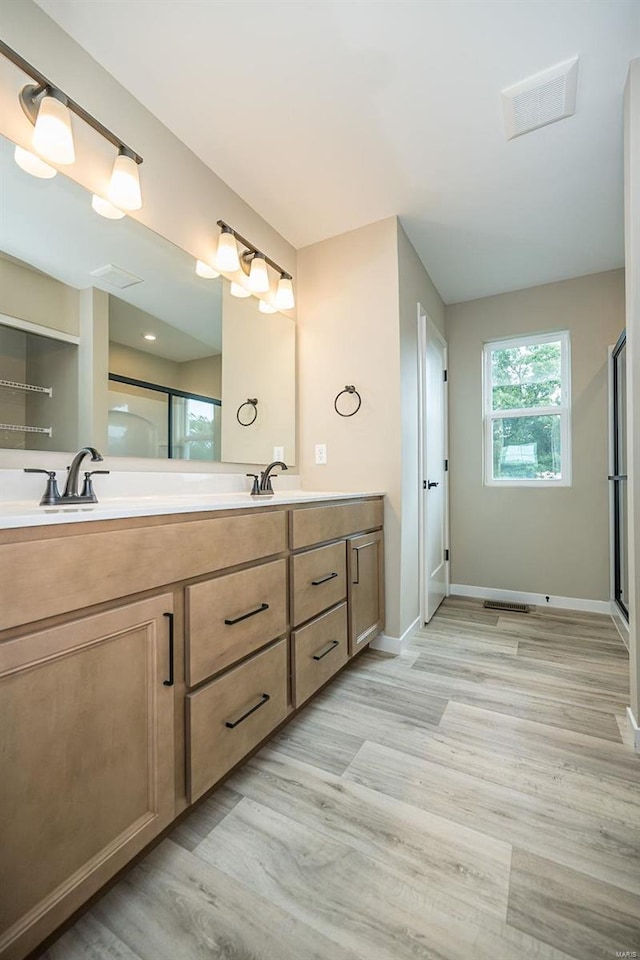 bathroom with wood finished floors, a sink, baseboards, and double vanity