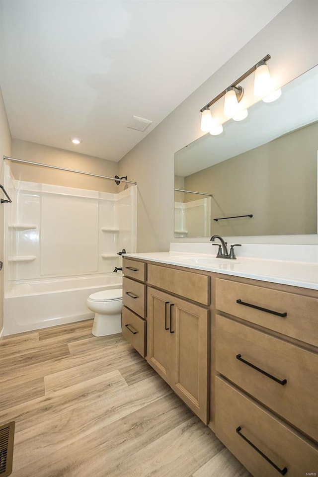 full bathroom with visible vents, toilet, wood finished floors, tub / shower combination, and vanity