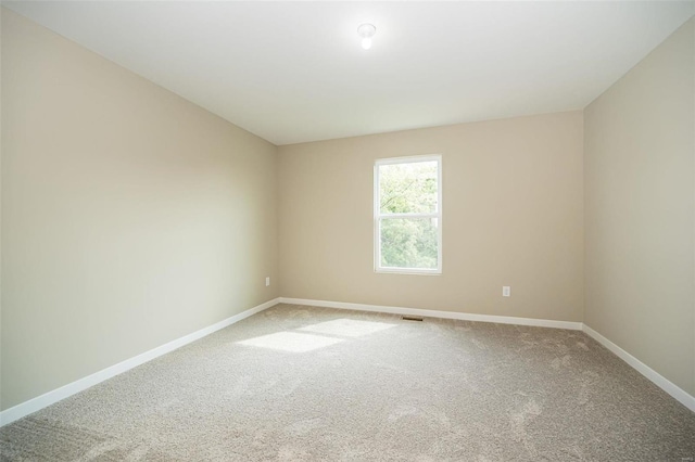 spare room featuring carpet, visible vents, and baseboards