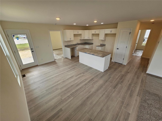 kitchen with sink, a kitchen island, white cabinets, and light wood-type flooring