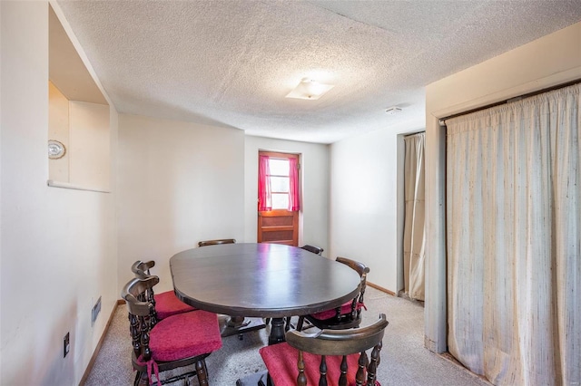 carpeted dining room featuring a textured ceiling