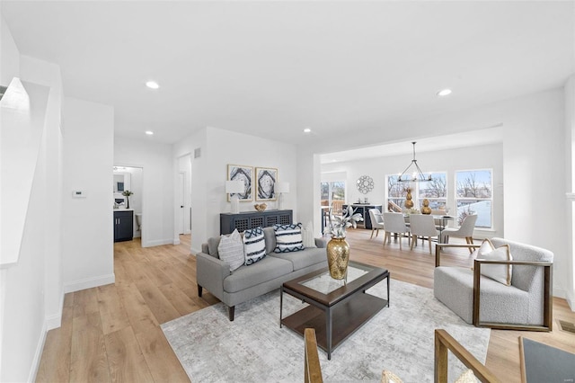 living room with a notable chandelier and light hardwood / wood-style flooring