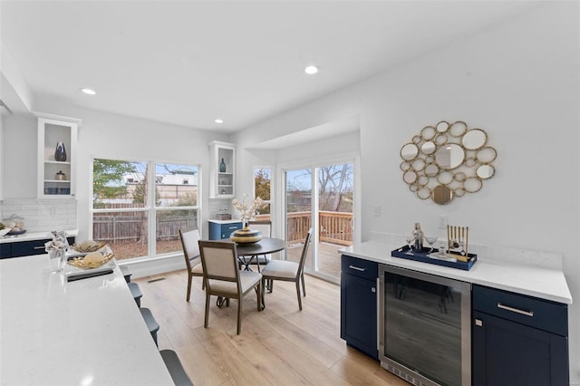 kitchen featuring blue cabinets, white cabinets, light hardwood / wood-style floors, beverage cooler, and tasteful backsplash