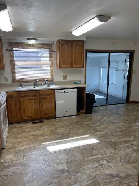 kitchen with range, light tile floors, a textured ceiling, dishwasher, and sink