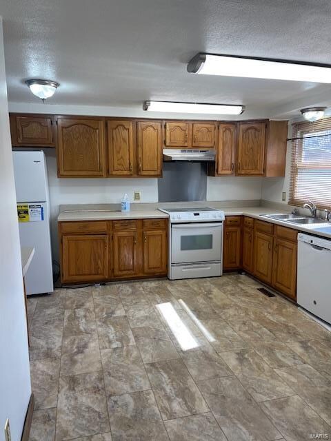 kitchen featuring white appliances, sink, and light tile floors