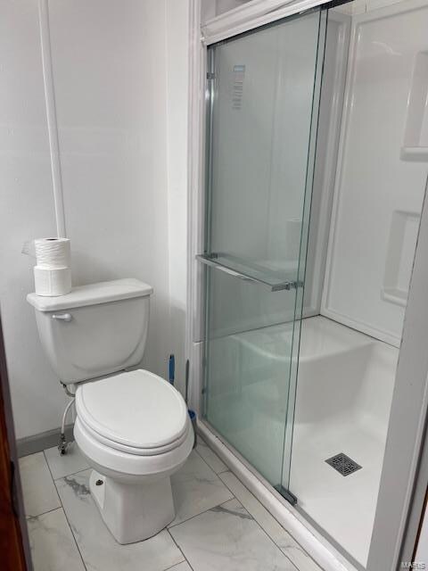 bathroom with an enclosed shower, tile floors, and toilet