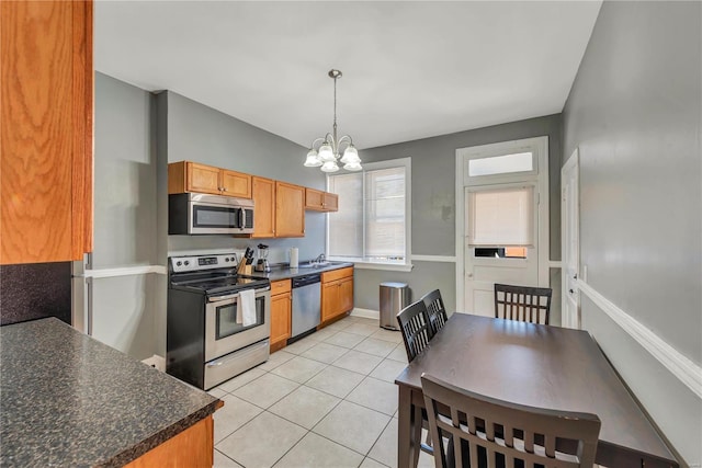 kitchen with sink, light tile floors, stainless steel appliances, decorative light fixtures, and a notable chandelier