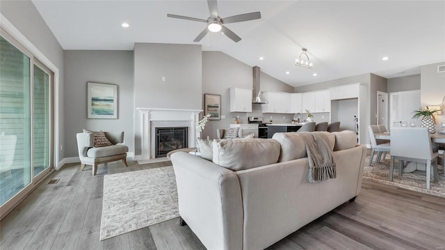 living room with high vaulted ceiling, light wood-type flooring, and ceiling fan with notable chandelier