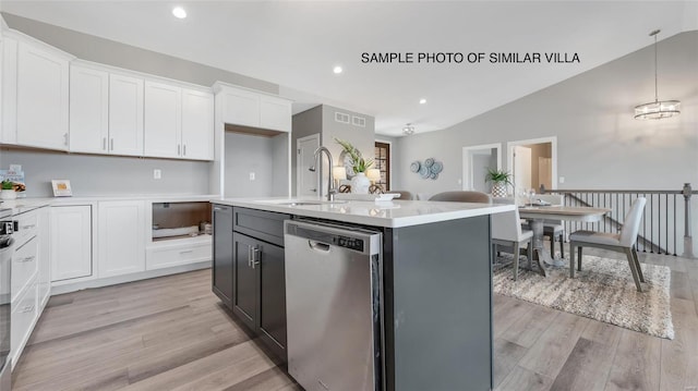 kitchen featuring stainless steel dishwasher, lofted ceiling, white cabinetry, light hardwood / wood-style flooring, and a kitchen island with sink