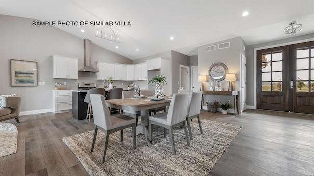 dining room featuring french doors, high vaulted ceiling, a chandelier, and hardwood / wood-style flooring