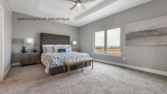 carpeted bedroom featuring ceiling fan and a raised ceiling