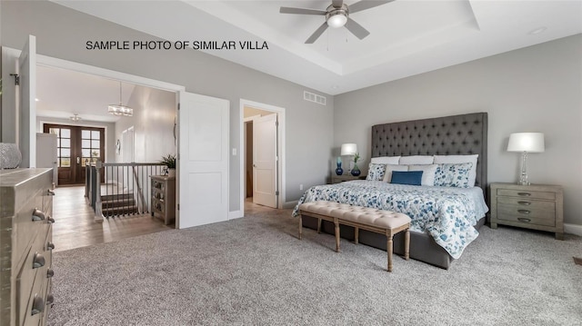 carpeted bedroom featuring ceiling fan, a tray ceiling, and french doors