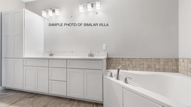 bathroom with double sink vanity, hardwood / wood-style flooring, and a tub