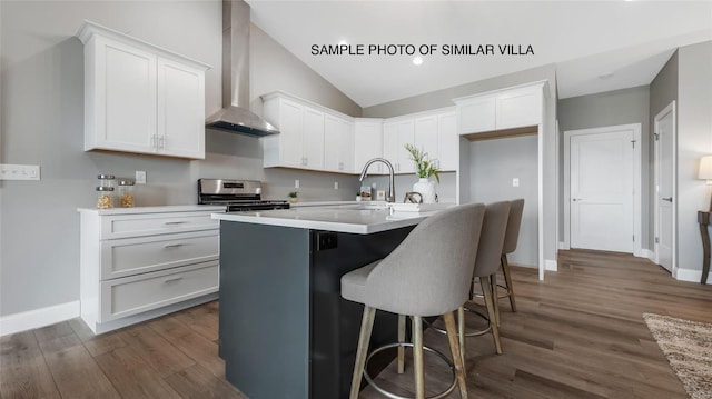 kitchen with wall chimney range hood, vaulted ceiling, white cabinets, range, and dark hardwood / wood-style flooring