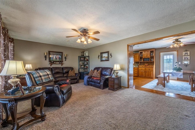 carpeted living room with a textured ceiling and ceiling fan