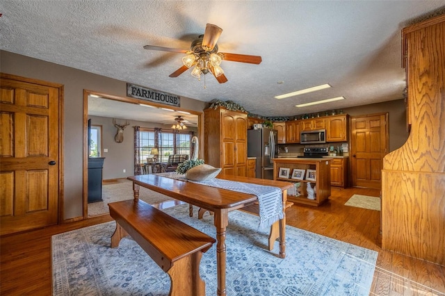 dining room featuring a textured ceiling, ceiling fan, and light wood-type flooring