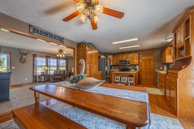 dining room featuring ceiling fan, light carpet, and a textured ceiling