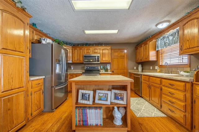 kitchen featuring light wood-type flooring, a center island, appliances with stainless steel finishes, and sink