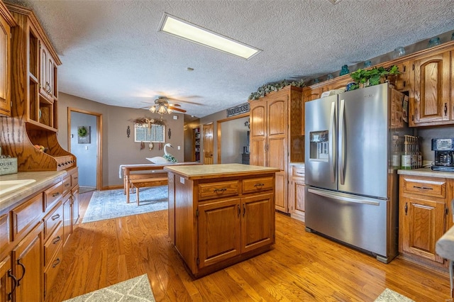 kitchen featuring light hardwood / wood-style floors, a kitchen island, stainless steel fridge with ice dispenser, ceiling fan, and a textured ceiling