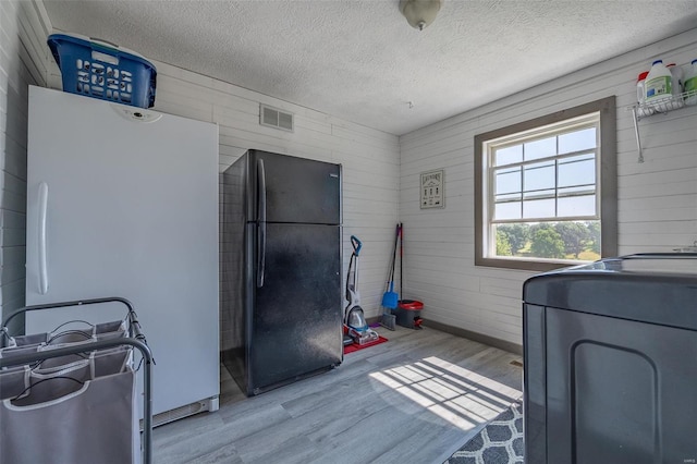 interior space featuring light hardwood / wood-style flooring, a textured ceiling, and washer / dryer