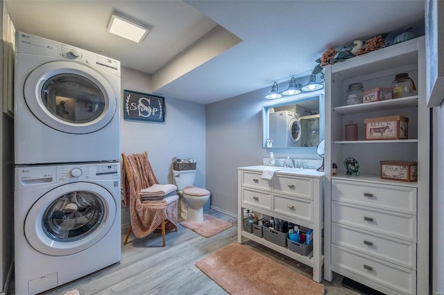 laundry area with stacked washer and dryer, sink, and light hardwood / wood-style floors