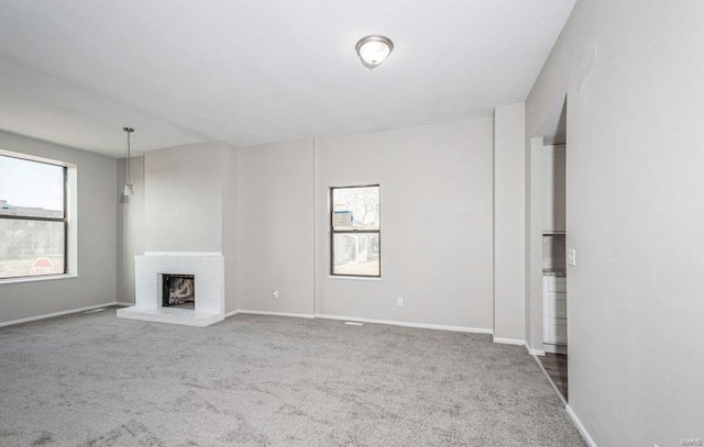 unfurnished living room featuring a brick fireplace and carpet flooring