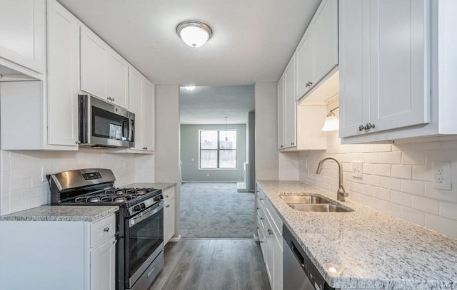 kitchen featuring light hardwood / wood-style floors, stainless steel appliances, white cabinetry, backsplash, and sink