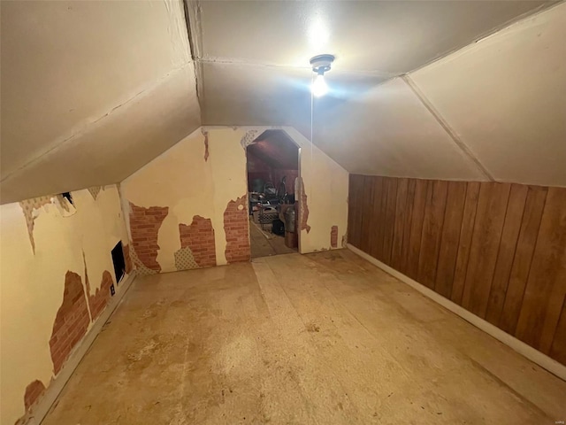 additional living space featuring wooden walls, lofted ceiling, and a fireplace