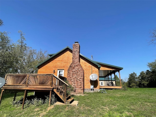 rear view of property featuring a wooden deck and a lawn