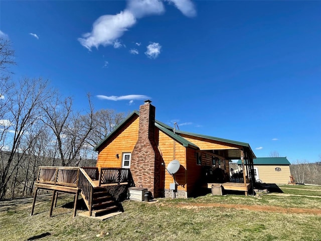 back of property featuring a wooden deck and a yard