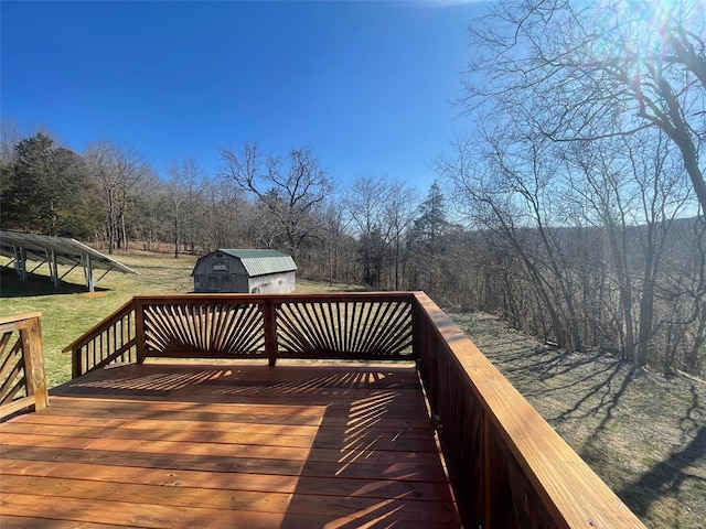 wooden terrace featuring a storage shed and a grill