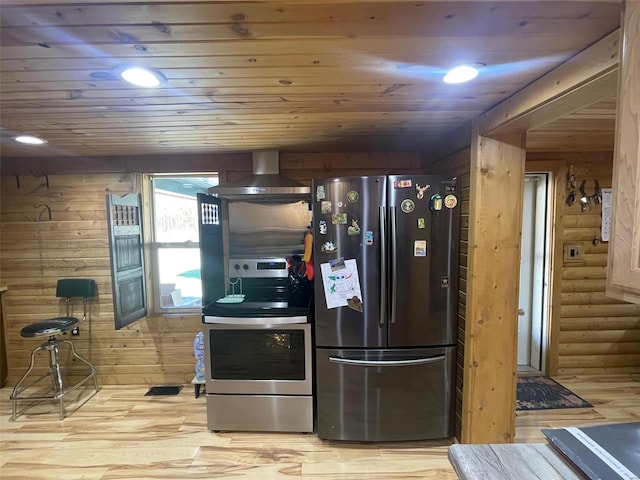 kitchen featuring appliances with stainless steel finishes, wood ceiling, wall chimney exhaust hood, wood walls, and light wood-type flooring