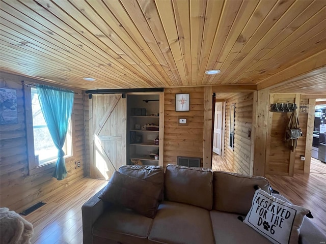 living room with wood-type flooring, wood walls, wooden ceiling, and a barn door