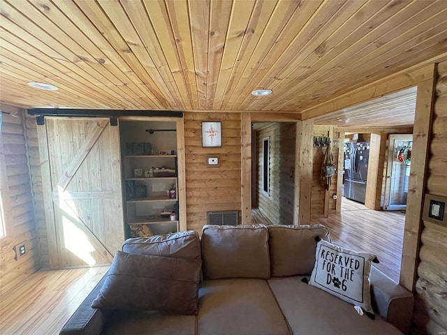 living room featuring wood walls, wooden ceiling, hardwood / wood-style floors, and a barn door