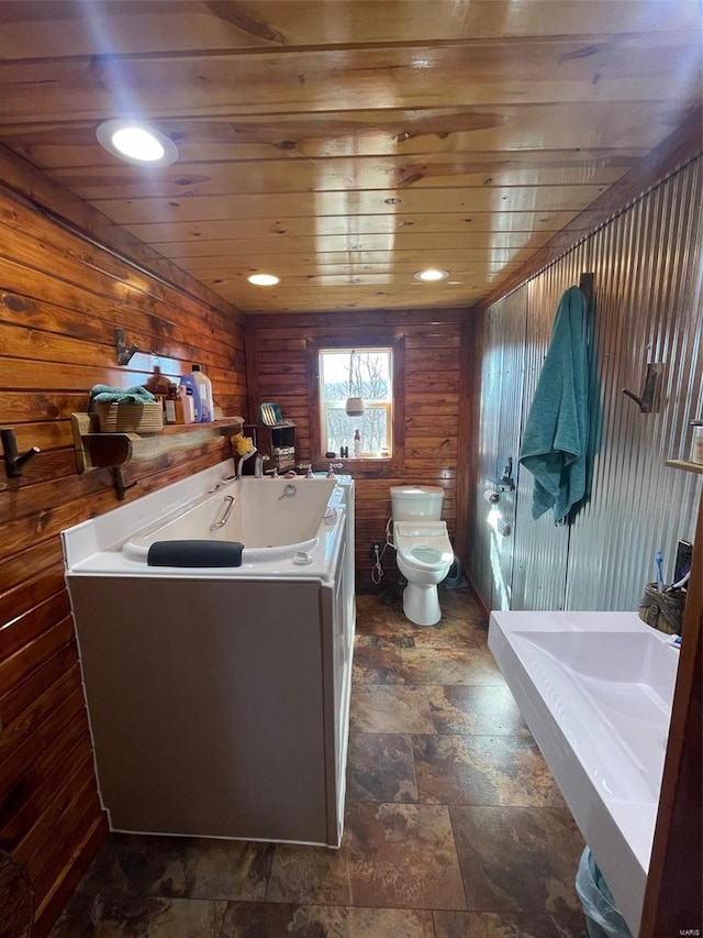 bathroom featuring a bathing tub, wood walls, toilet, and wooden ceiling