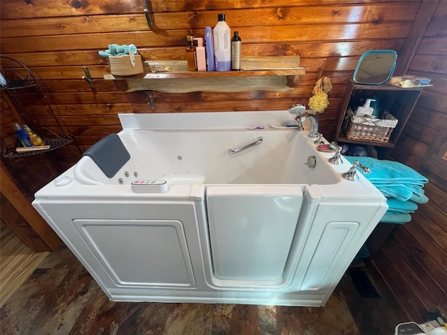 bathroom featuring wooden walls, a tub to relax in, and hardwood / wood-style flooring