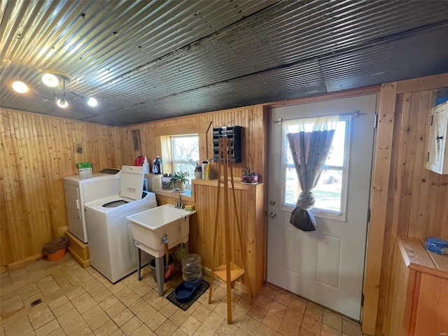 laundry area with wood walls, sink, and washing machine and dryer