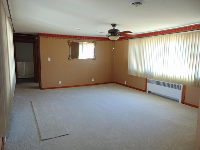 empty room with ceiling fan, radiator, and light colored carpet