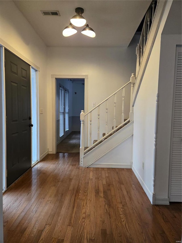 entrance foyer featuring visible vents, stairs, baseboards, and wood finished floors