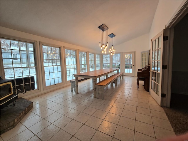 dining area with light tile patterned floors, lofted ceiling, an inviting chandelier, and a wood stove