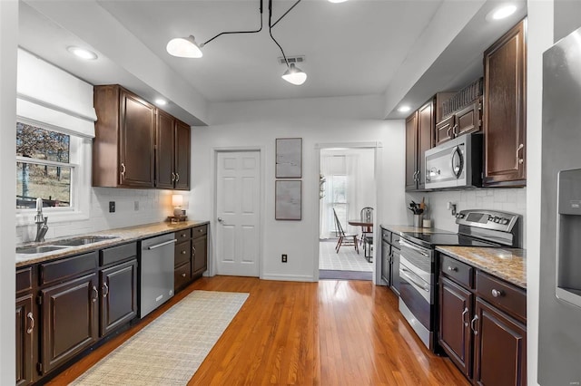 kitchen with tasteful backsplash, light countertops, light wood-style flooring, stainless steel appliances, and a sink