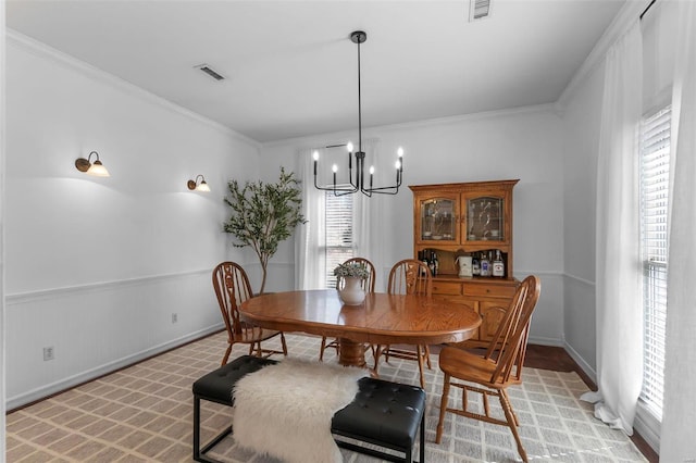 dining room with an inviting chandelier, crown molding, and visible vents