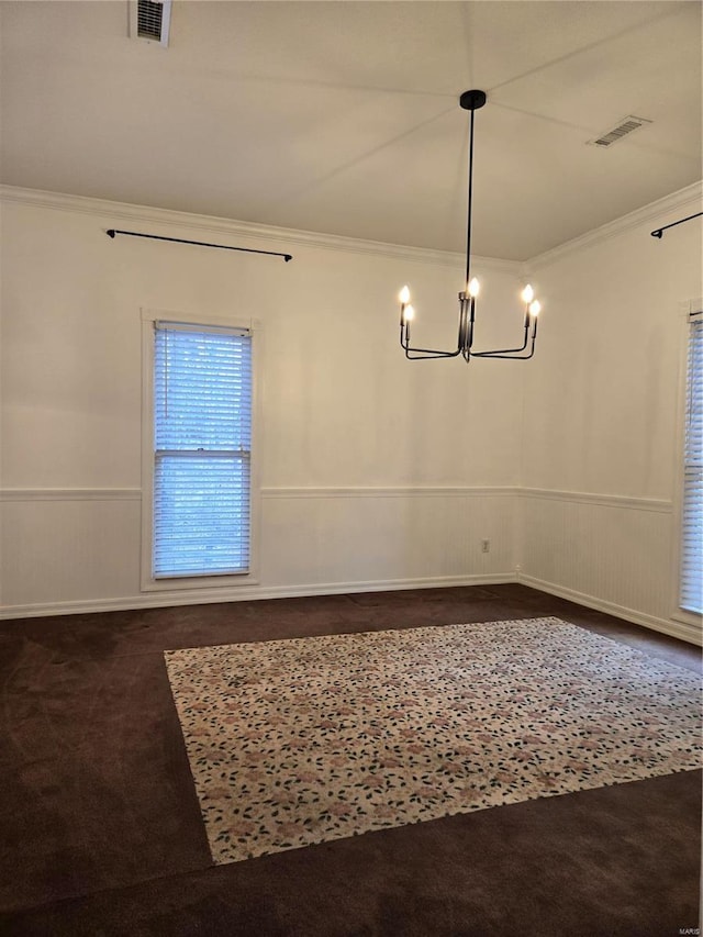 spare room with visible vents, dark carpet, wainscoting, and crown molding