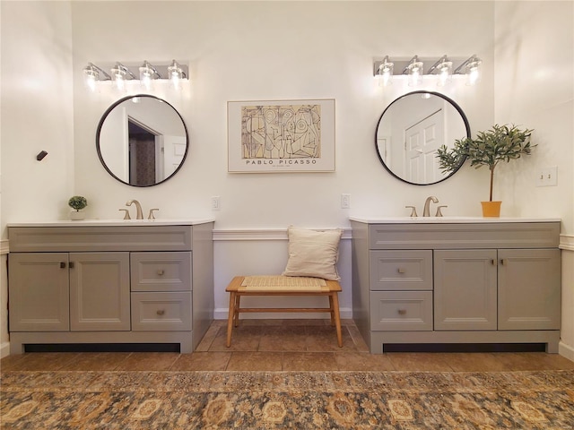 bathroom with a sink, baseboards, and two vanities